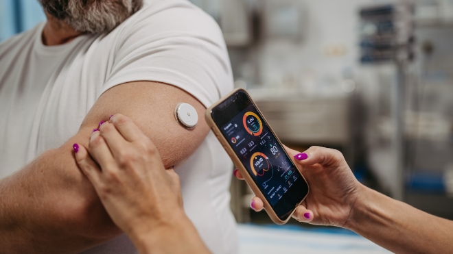 Medical phone software being used to communicate with a monitor placed on a mans skin.
