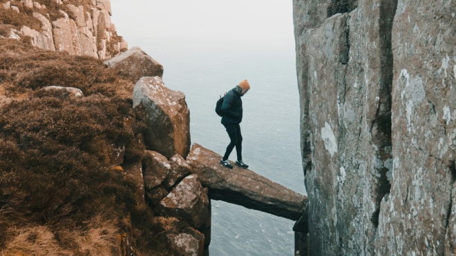 A man carefully steps across a cliff-face. An analogy for assessing risk.